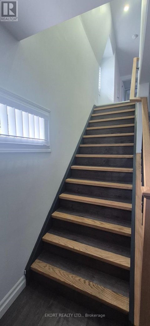 A wooden staircase with a white wall and a window.