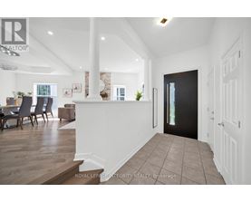 A spacious hallway with a dining area and a kitchen in the background.