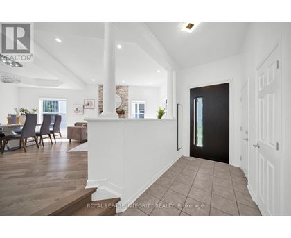 A spacious hallway with a dining area and a kitchen in the background.
