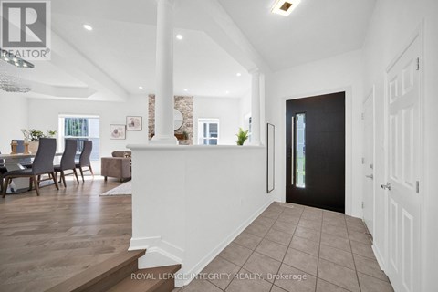 A spacious hallway with a dining area and a kitchen in the background.