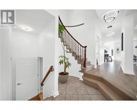 A white hallway with a staircase and a plant on the landing.