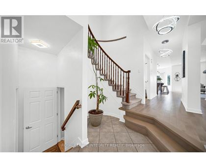 A white hallway with a staircase and a plant on the landing.