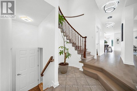 A white hallway with a staircase and a plant on the landing.