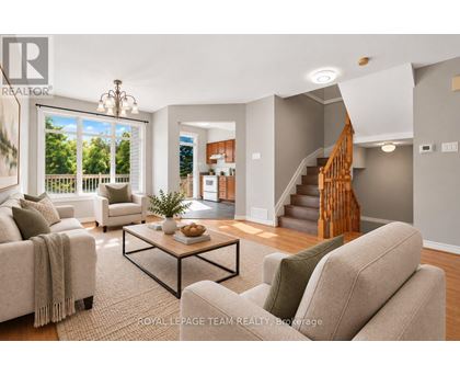A living room with a couch, coffee table, and staircase.