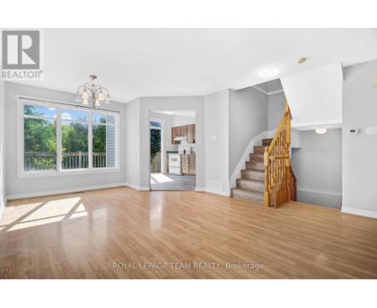 A spacious room with wooden floors and a staircase leading to another room.