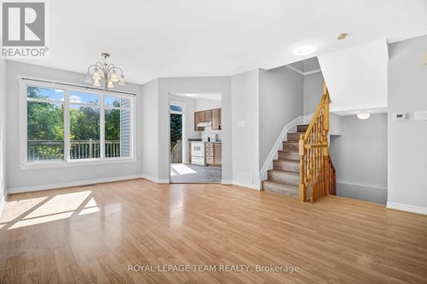 A spacious room with wooden floors and a staircase leading to another room.