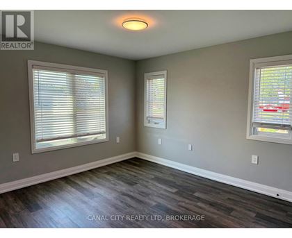A room with wood flooring and two windows.