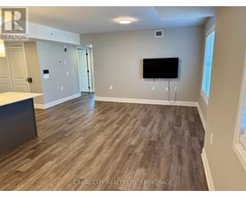 A room with wooden flooring and a flat screen TV mounted on the wall.