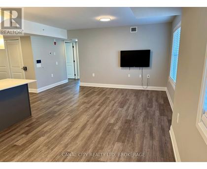 A room with wooden flooring and a flat screen TV mounted on the wall.