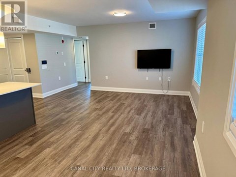 A room with wooden flooring and a flat screen TV mounted on the wall.