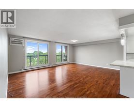 A room with wooden floors and a large window with a view of trees.