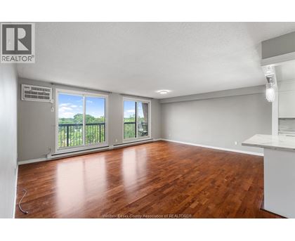 A room with wooden floors and a large window with a view of trees.