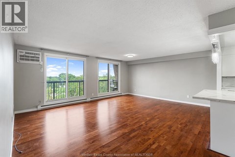 A room with wooden floors and a large window with a view of trees.