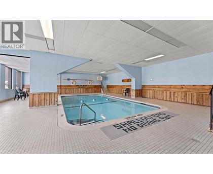 A swimming pool in a room with a tiled floor and a wooden wall.