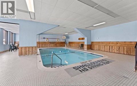 A swimming pool in a room with a tiled floor and a wooden wall.
