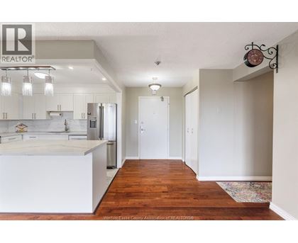 A kitchen with white cabinets and a wooden floor.