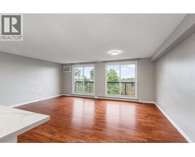 A spacious room with wooden flooring and a sliding glass door leading to a balcony.