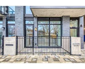 A modern house entrance with a black gate and a concrete pillar.