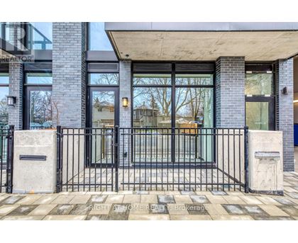 A modern house entrance with a black gate and a concrete pillar.