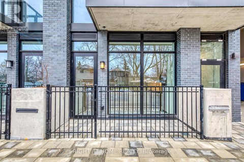 A modern house entrance with a black gate and a concrete pillar.