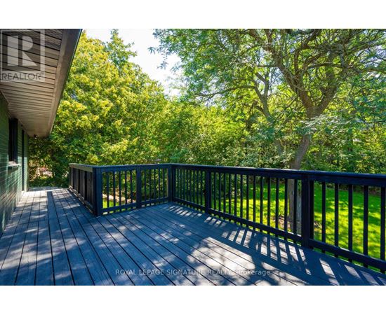 A wooden deck with a railing and trees in the background.
