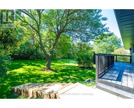 A wooden deck leads to a lush green backyard.