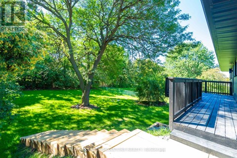 A wooden deck leads to a lush green backyard.