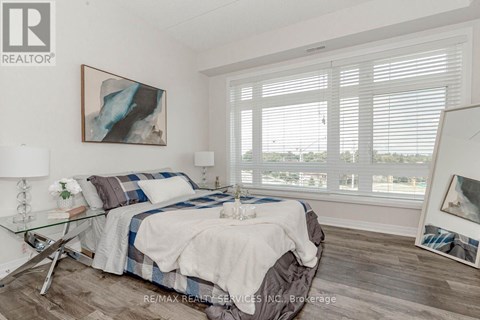 A bedroom with a bed, a glass table, and a painting on the wall.