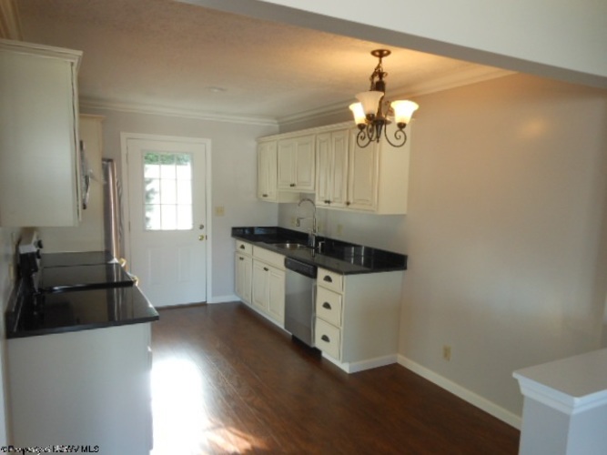 A kitchen with white cabinets and black countertops.