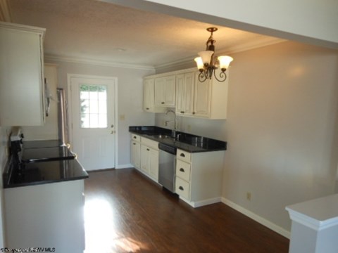 A kitchen with white cabinets and black countertops.