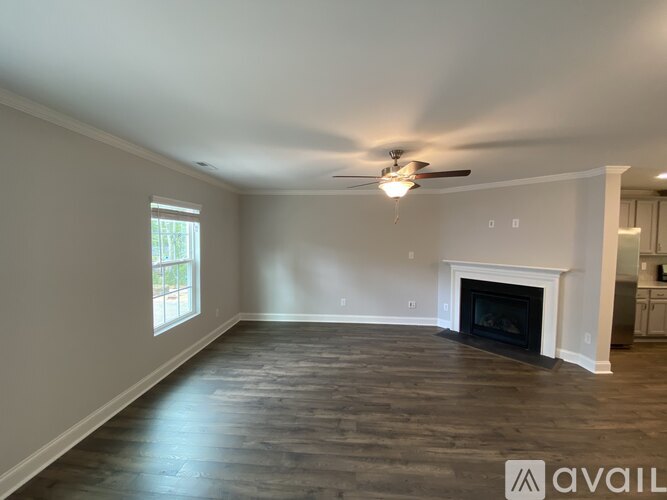 A spacious living room with a fireplace and a ceiling fan.