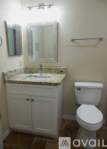 A bathroom with a toilet, sink, and mirror.