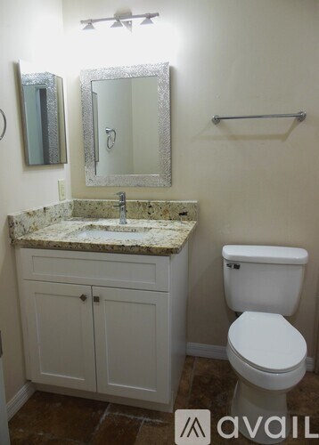 A bathroom with a toilet, sink, and mirror.