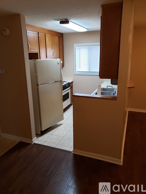A kitchen with a white refrigerator and wooden cabinets.