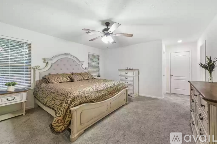A bedroom with a bed, dresser, and ceiling fan.