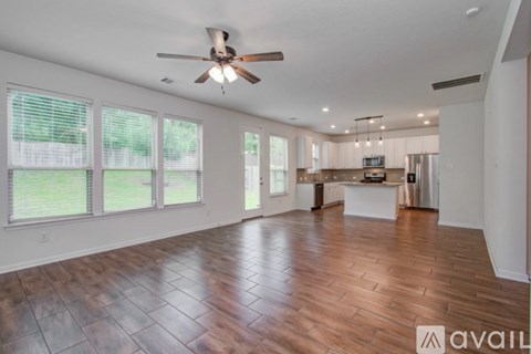 A spacious room with wooden flooring and a ceiling fan.