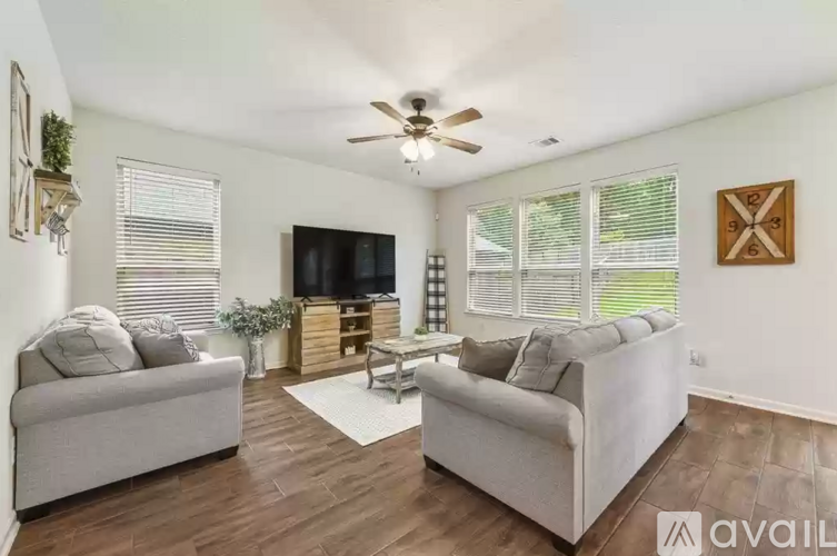 A living room with a grey couch, a white couch, a wooden entertainment center, and a ceiling fan.