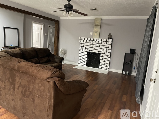 A living room with a brown couch and a fireplace.