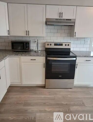 A kitchen with a black stove top oven and white cabinets.