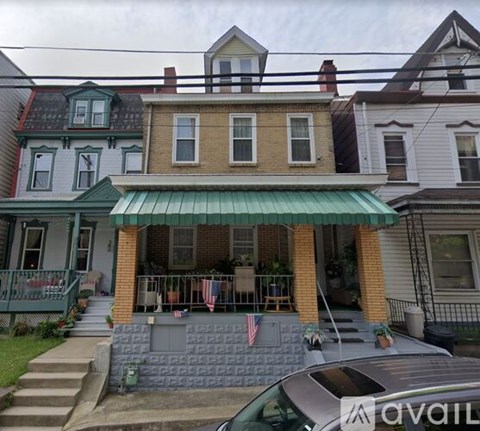 A house with a green awning and a car parked in front.