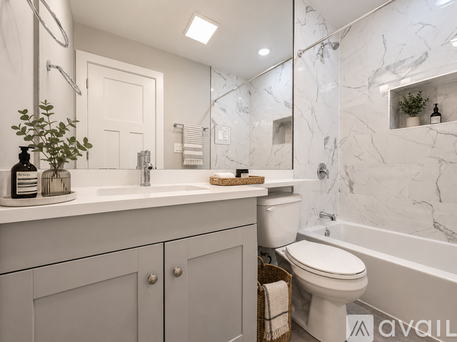 A white bathroom with a marble wall and a white toilet.