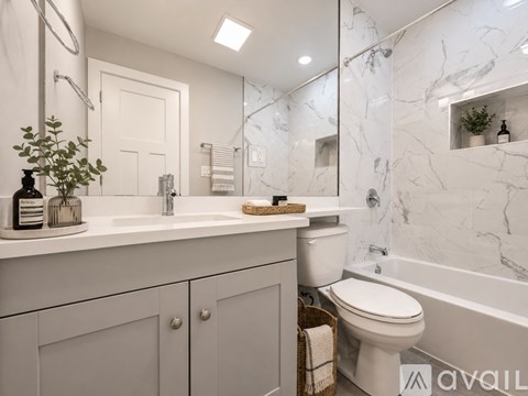 A white bathroom with a marble wall and a white toilet.