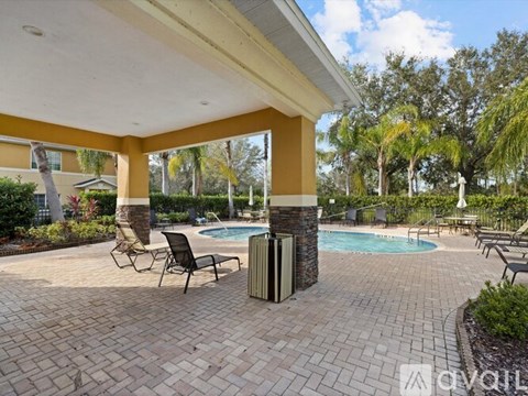 A pool area with a yellow building and a pool in the middle.