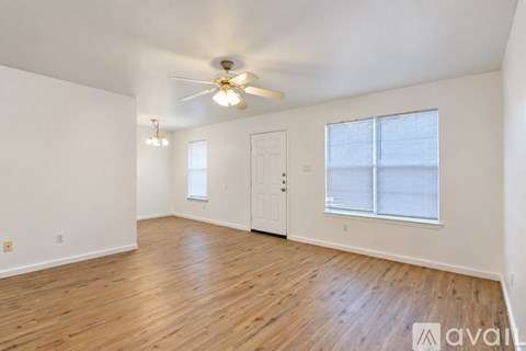 A spacious room with wooden flooring and a ceiling fan.