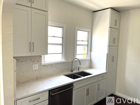 A kitchen with white cabinets and a marble countertop.