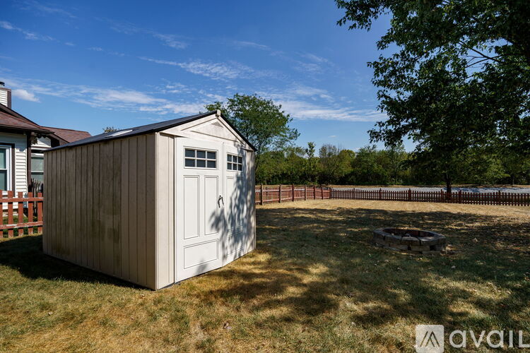 A wooden shed sits in a grassy field.