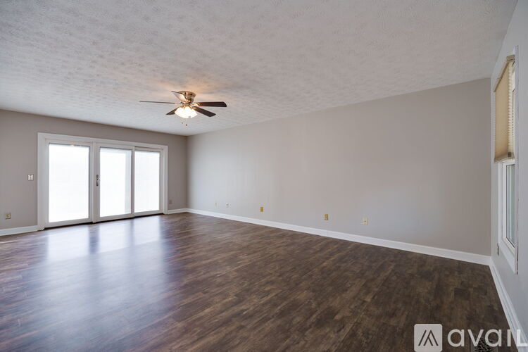 A spacious room with a ceiling fan and sliding glass doors.