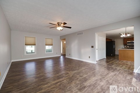 A spacious living room with a ceiling fan and hardwood flooring.