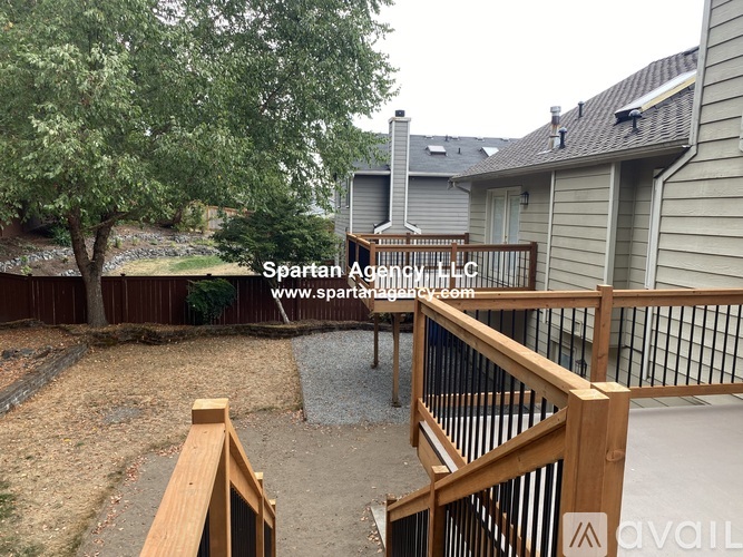 A backyard with a wooden deck and a tree.