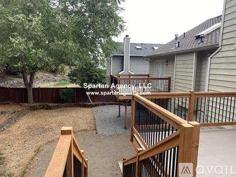 A backyard with a wooden deck and a tree.